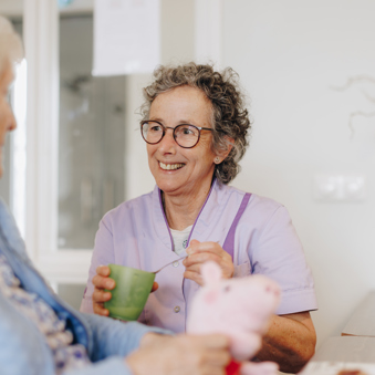 De Waterpoort Zorgpartners Bewoner Medewerker Eten Helpen Bord Tafel Rolstoel Interactie Lachen