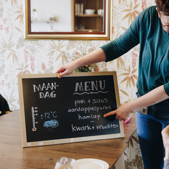 De Waterpoort Zorgpartners Woonkamer Tafel Bewoners Medewerker Menu Krijtbord