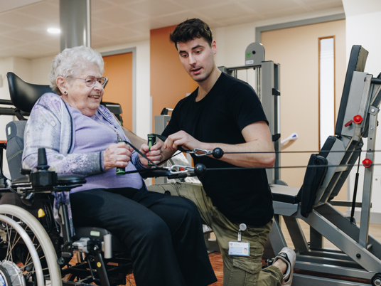 10 02 2023 Zorgpartners Savelberg Bewoner Fysiotherapeut Rolstoel Fitness Apparaat